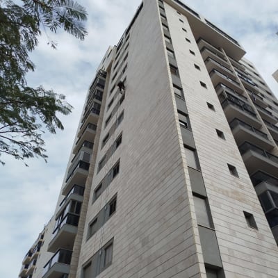 אדם עובד על בניין גבוה באמצעות חבלים