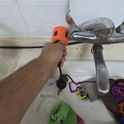 יד מחזיקה מכשיר ליד ברז בכיור מטבח