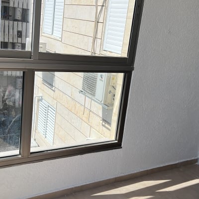 מרפסת עם חלונות גדולים, קיר לבן ורצפת אריחים