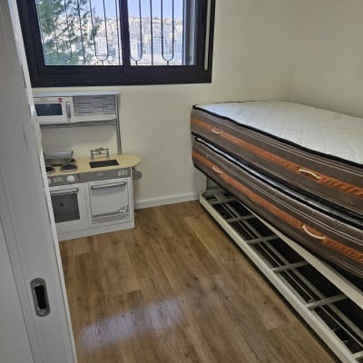 חדר עם רצפת עץ ומזרנים מונחים על מסגרת מתכת