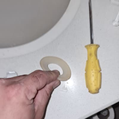 יד מחזיקה אטם ליד כיור ומברג צהוב