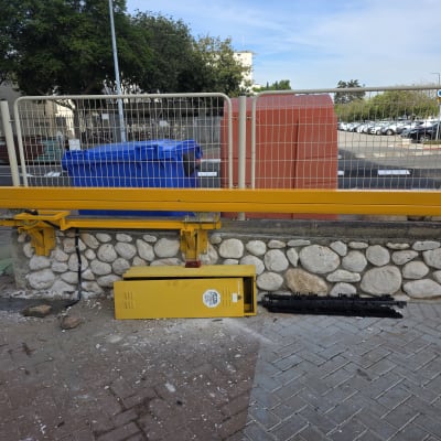 שער חשמלי צהוב מותקן על קיר אבן עם שער מתכת.