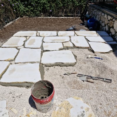 אבנים מונחות על אדמה עם כלי עבודה לגינון