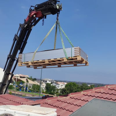 מנוף מרים לוחות סולאריים על גג רעפים אדום