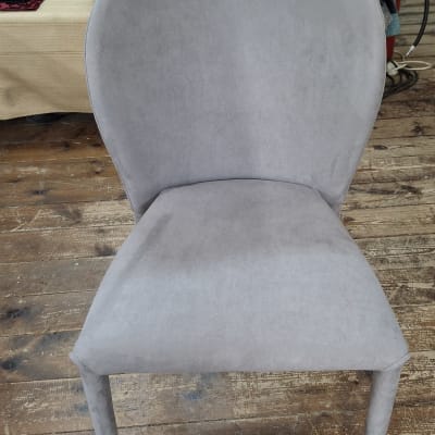 כיסא מרופד עם בדים ברקע על רצפת עץ