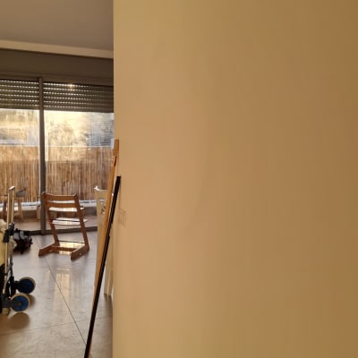 מגב עומד ליד קיר לבן במסדרון מואר