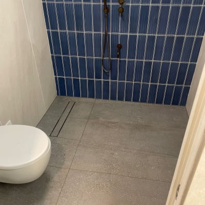 חדר אמבטיה עם אריחים כחולים ואסלה מותקנת