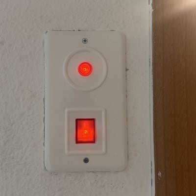 מתג חשמלי עם נורית חיווי אדומה על קיר