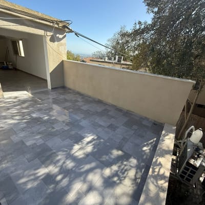 מרפסת מרוצפת עם נוף ועצים ברקע