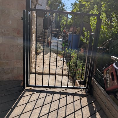 שער מתכת בכניסה לחצר עם צללים על הרצפה