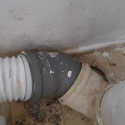 צינור פלסטיק לבן עם חיבור אפור על רצפה מלוכלכת