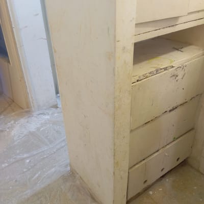 ארון ישן עם סימני צבע ופלסטיק על הרצפה