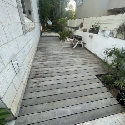 דק עץ בגינה עם עציצים וצמחים מסביב