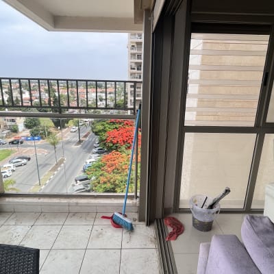 מטאטא כחול ואדום, דלי עם מברשות וסמרטוט אדום על מרפסת