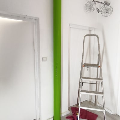 סולם, צינור ירוק, כלי עבודה וציוד צביעה על הרצפה