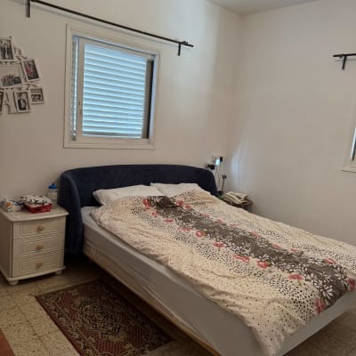 חדר שינה עם מיטה זוגית, שידה וחלון עם תריסים