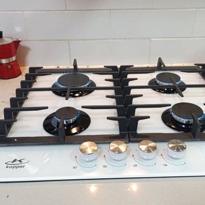 כיריים גז לבנים עם ארבעה מבערים וכפתורי שליטה כסופים