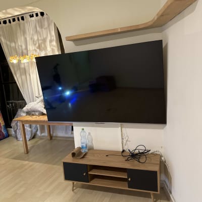 טלוויזיה תלויה על הקיר עם מדף עץ מעל