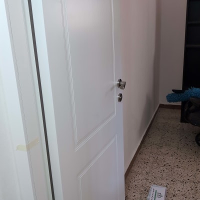 דלת לבנה עם ידית כסופה פתוחה חלקית