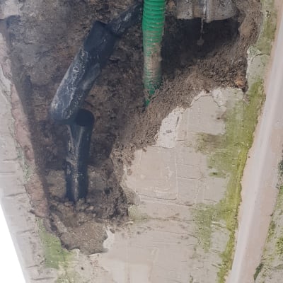 צינור ירוק ושחור בקיר חשוף עם טיח מתקלף