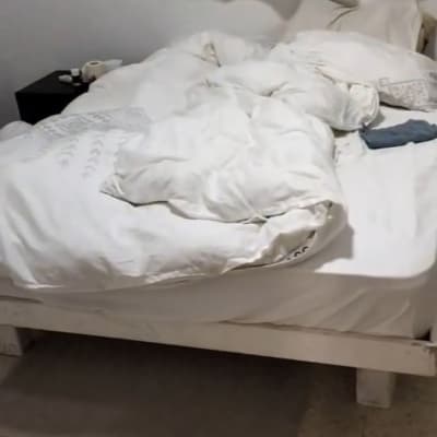 מיטה עם מצעים מבולגנים וחפצים על הרצפה