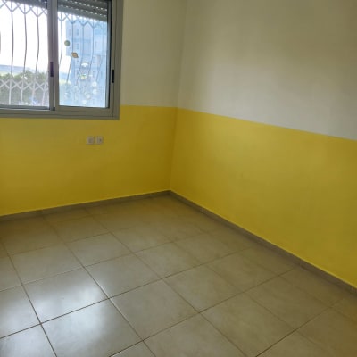 חדר צבוע בצהוב ולבן עם חלון סגור