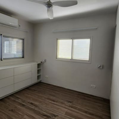 חדר עם רצפת עץ, חלונות ותריסים, מזגן ותקרה עם מאוורר