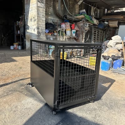 כלוב מתכת על גלגלים בחצר עם ציוד בנייה