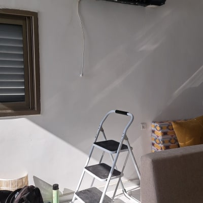 מזגן מפורק על קיר עם סולם מתחתיו