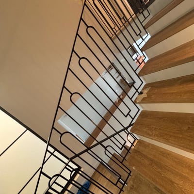 מעקה מתכת שחור עם עיצוב גיאומטרי על מדרגות עץ