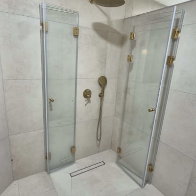 מקלחת עם דלתות זכוכית וברזים מוזהבים