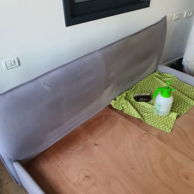 ניקוי ספה עם חומר ניקוי ומברשת על בד אפור