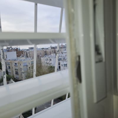 תריסים לבנים פתוחים עם נוף עירוני ברקע