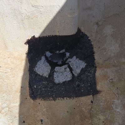 איטום פינה עם חומר שחור על קיר בטון