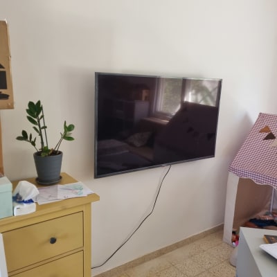 טלוויזיה מותקנת על קיר עם כבל חשמל גלוי