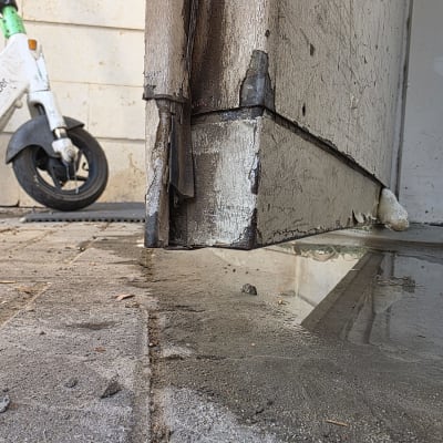 דלת עץ פגומה עם סימני ריקבון ומים על הרצפה