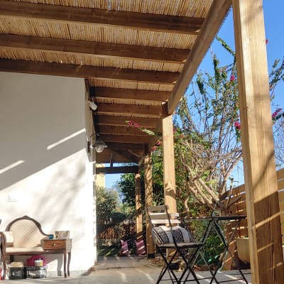פרגולה מעץ עם גג קנים בחצר