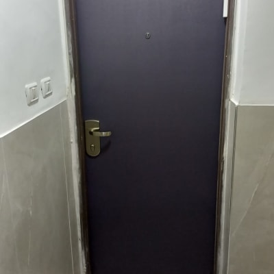 דלת כהה עם ידית מתכת ומסגרת בהירה