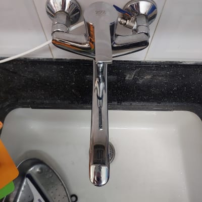 ברז כרום מעל כיור עם אריחי קרמיקה לבנים