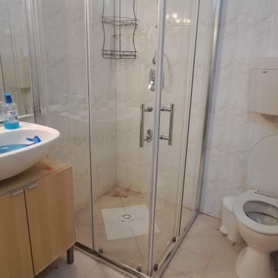 מקלחון זכוכית עם ראש מקלחת ומדף מתכת