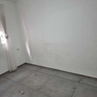 קיר לבן עם רצפת אריחים וחלון עם וילון