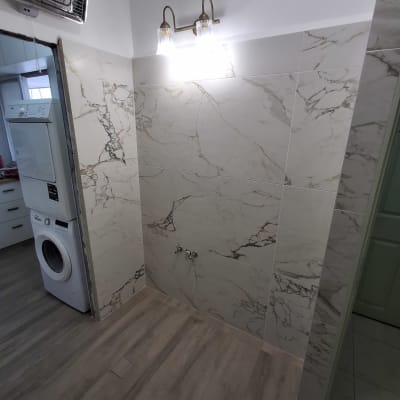 חדר אמבטיה עם אריחים חדשים ומכונת כביסה