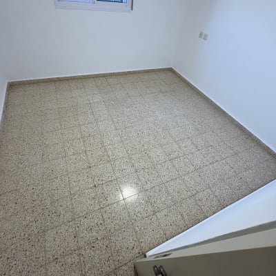 חדר ריק עם רצפת אריחים וחלון