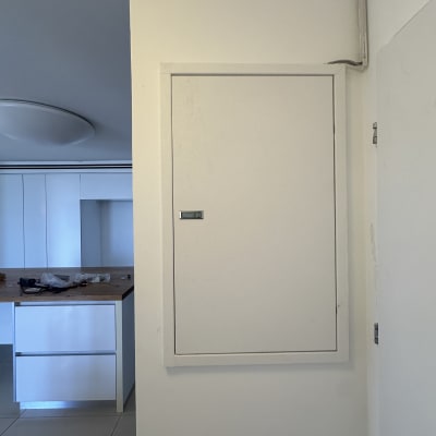 ארון חשמל לבן על קיר לבן עם צינור חשמל