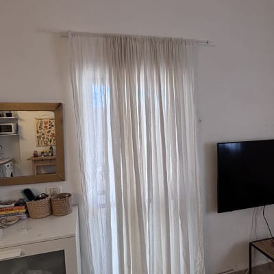 וילון לבן תלוי על חלון ליד טלוויזיה