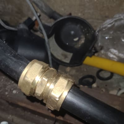 צינור שחור עם מחבר פליז על רקע קיר