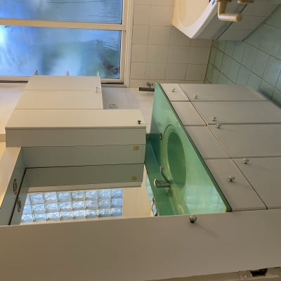 כיור ירוק עם ארונות לבנים בחדר אמבטיה