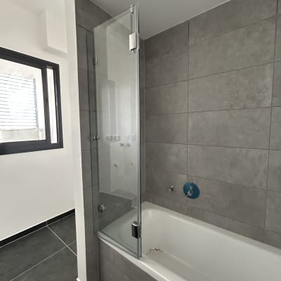 אמבטיה עם דלת זכוכית ומקלחת קיר