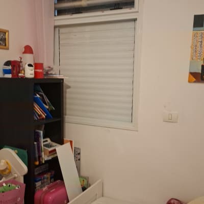 חדר עם חלון תריס וכלי עבודה על המיטה