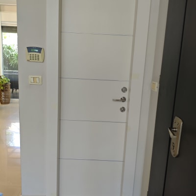 דלת לבנה עם ידית וכפתור ליד לוח מקשים